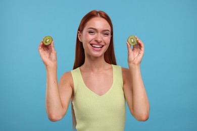 Photo of Happy woman with halves of fresh kiwi on light blue background