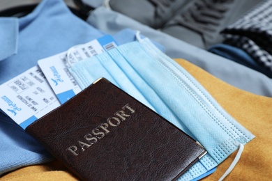 Photo of Passport with protective mask and tickets in suitcase, closeup