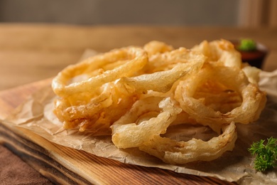 Photo of Homemade delicious golden breaded and deep fried crispy onion rings on wooden board, closeup