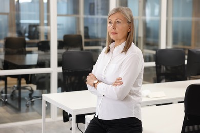 Photo of Confident woman with crossed arms in office. Lawyer, businesswoman, accountant or manager