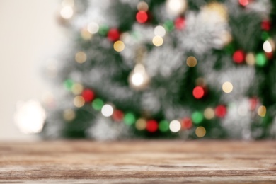 Photo of Empty wooden table and blurred fir tree with Christmas lights on background, bokeh effect. Space for design