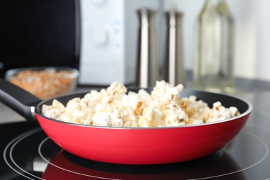 Frying pan with tasty popcorn on stove in kitchen