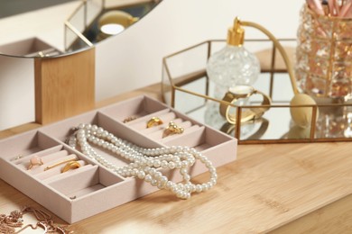 Photo of Jewelry box with many different accessories and perfume on wooden table