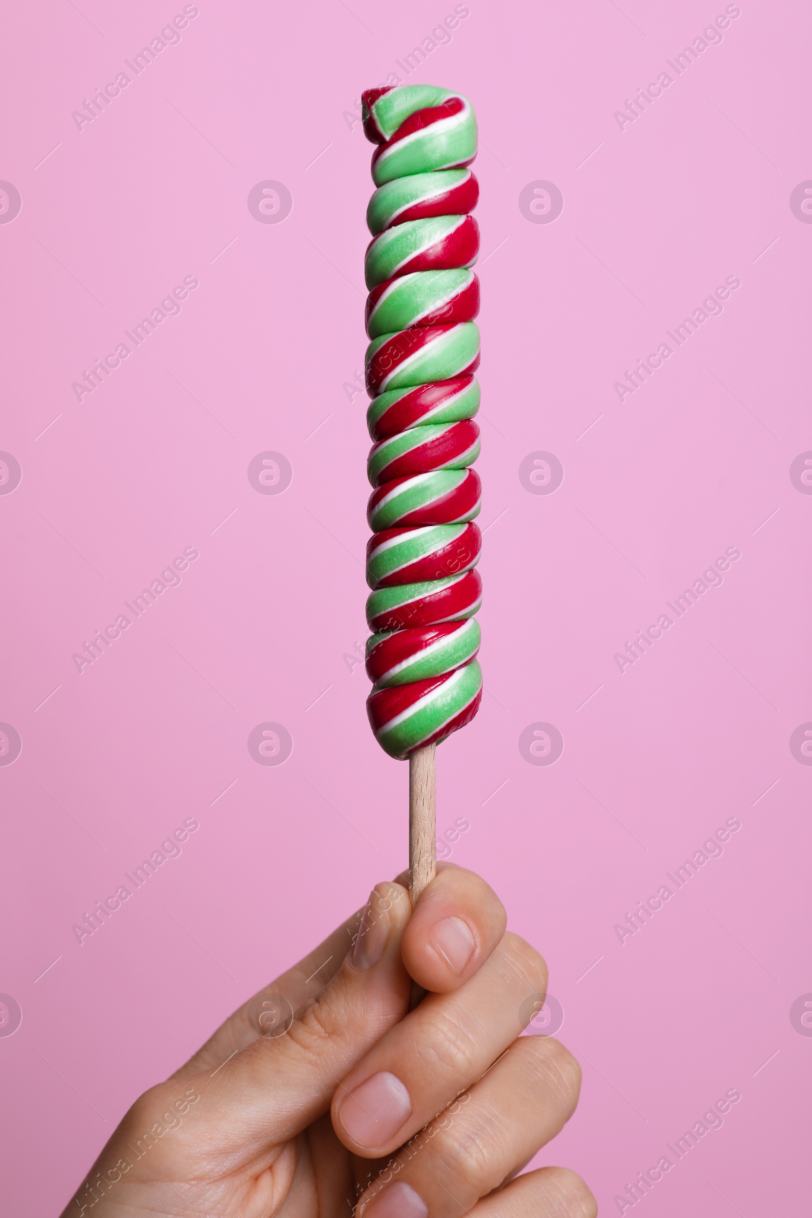 Photo of Woman holding bright tasty lollipop on pink background, closeup