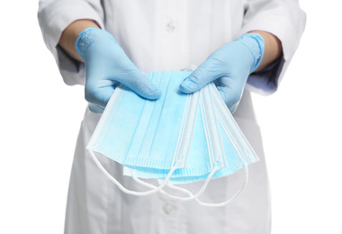 Doctor in latex gloves holding disposable face masks on white background, closeup. Protective measures during coronavirus quarantine