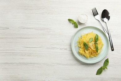 Photo of Tasty spaghetti squash with basil and cheese served on white wooden table, flat lay. Space for text