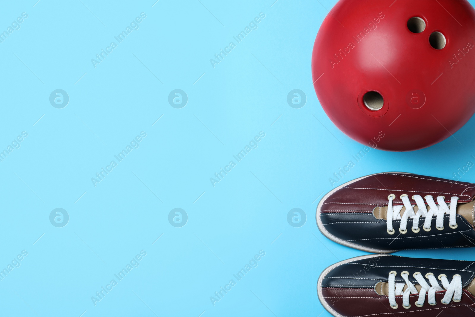 Photo of Bowling ball and shoes on light blue background, flat lay. Space for text