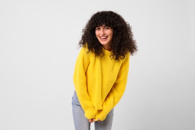 Photo of Happy young woman in stylish yellow sweater on white background