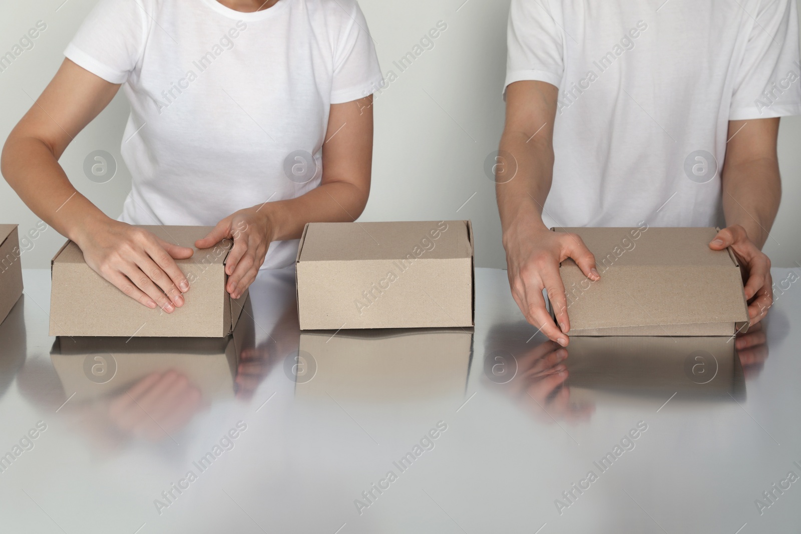 Photo of Workers folding cardboard boxes at table, closeup. Production line 