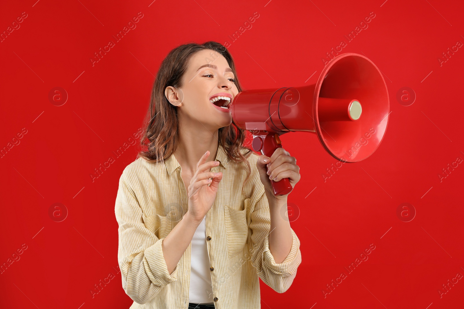 Photo of Young woman with megaphone on red background