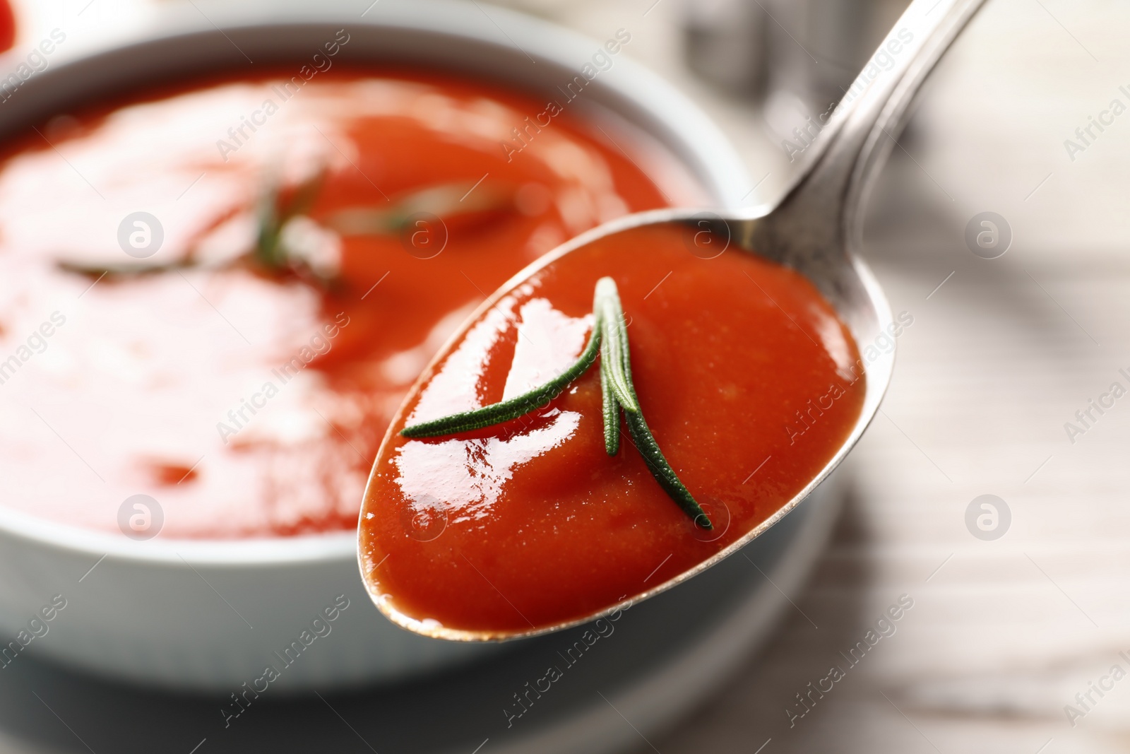 Photo of Spoon with fresh homemade tomato soup on blurred background, closeup