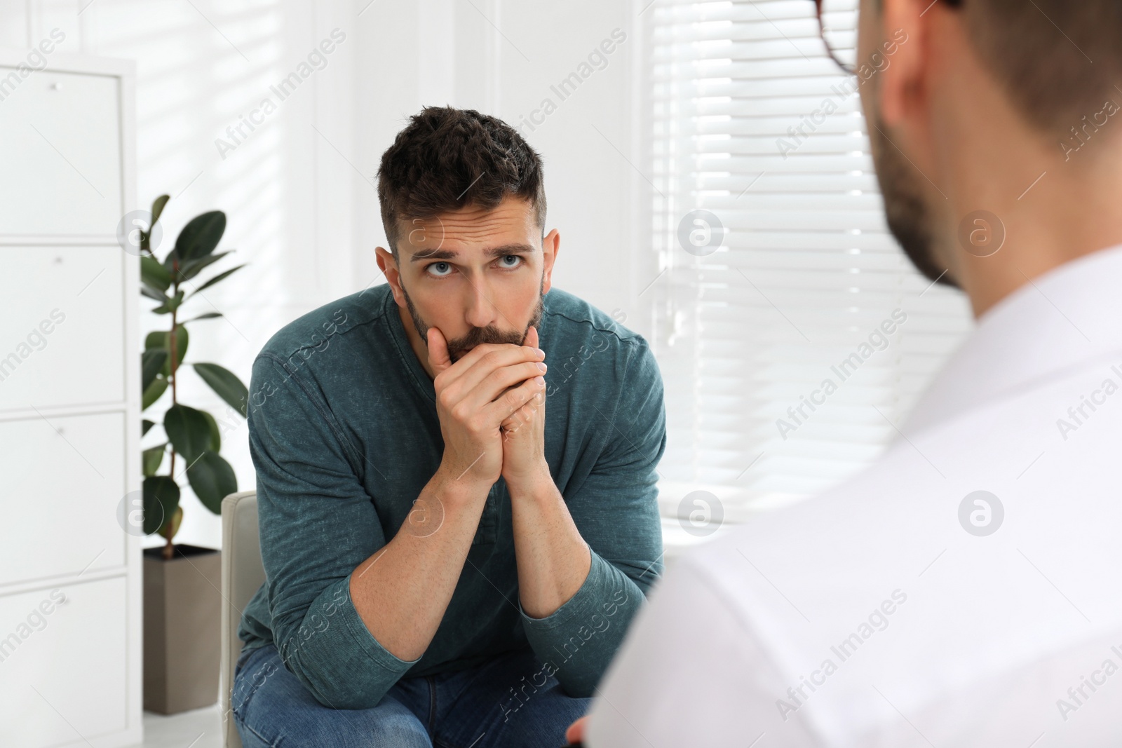 Photo of Psychotherapist working with drug addicted man indoors