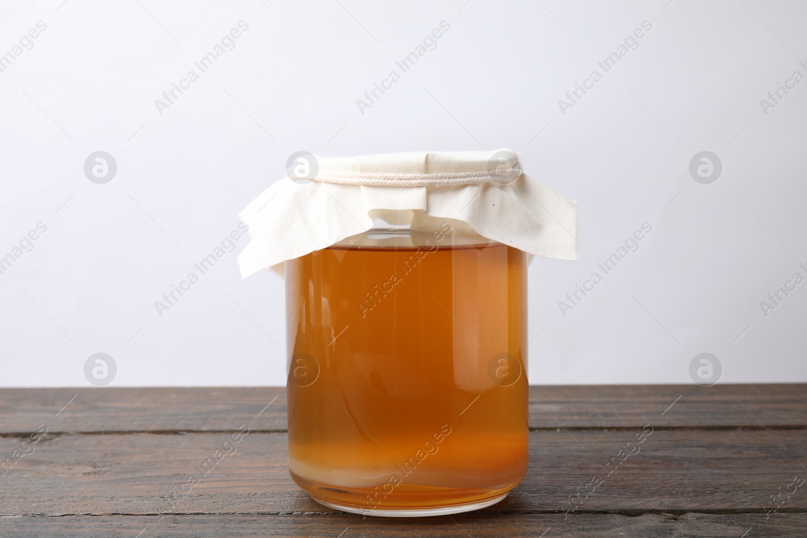 Photo of Homemade fermented kombucha in glass jar on wooden table