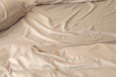 Photo of Bed with stylish silky linens, closeup view