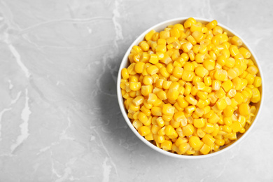 Photo of Delicious canned corn in bowl on marble table, top view. Space for text