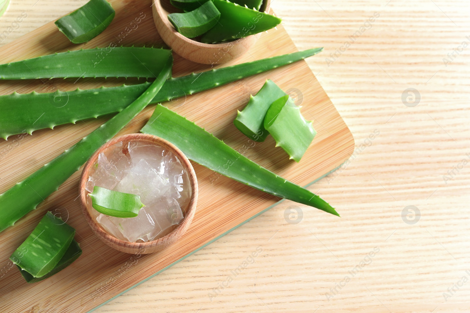 Photo of Flat lay composition with bowl of peeled aloe vera and green leaves on wooden table