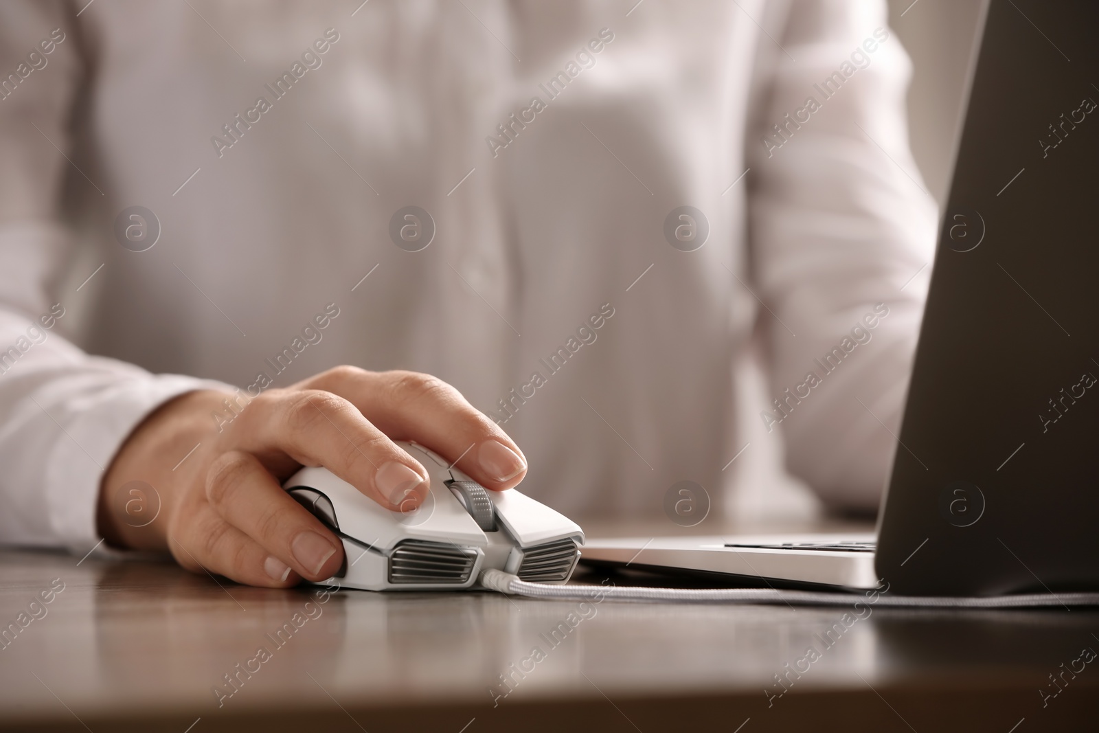 Photo of Woman using computer mouse with laptop at table, closeup