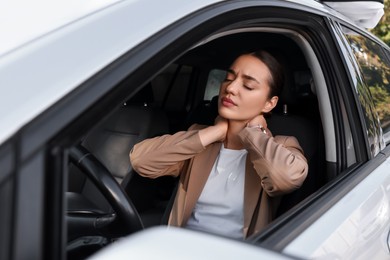 Young woman suffering from neck pain in her car