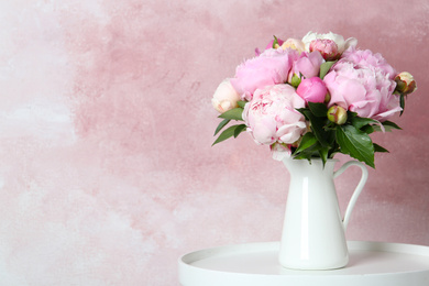 Bouquet of beautiful peonies in vase on white table. Space for text