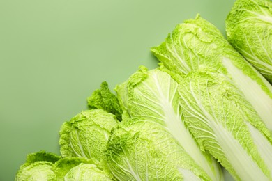 Many fresh Chinese cabbages on pale green background, top view. Space for text