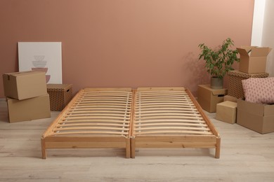 Photo of Wooden bed frame and cardboard boxes on floor in room