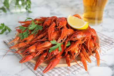 Delicious boiled crayfishes on white marble table, closeup