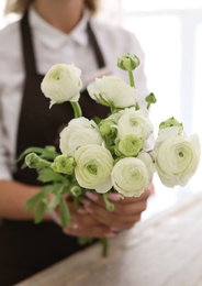 Female florist holding beautiful flowers in shop