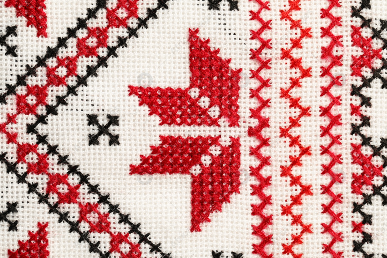 Photo of Traditional Ukrainian embroidery on white canvas as background, closeup. National handicraft