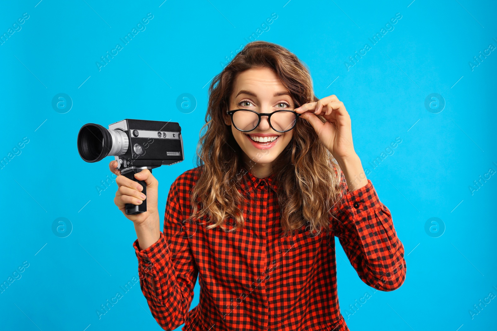 Photo of Beautiful young woman with vintage video camera on light blue background