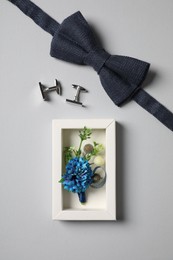 Photo of Wedding stuff. Stylish boutonniere, bow tie and cufflinks on gray background, flat lay