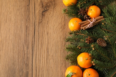 Photo of Christmas composition with tangerines on wooden background, flat lay. Space for text