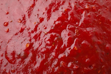 Photo of Tasty red spicy sauce as background, closeup