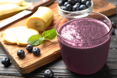 Fresh acai drink with banana and berries on dark wooden table, closeup