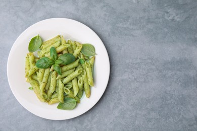 Photo of Delicious pasta with pesto sauce and basil on light grey table, top view. Space for text
