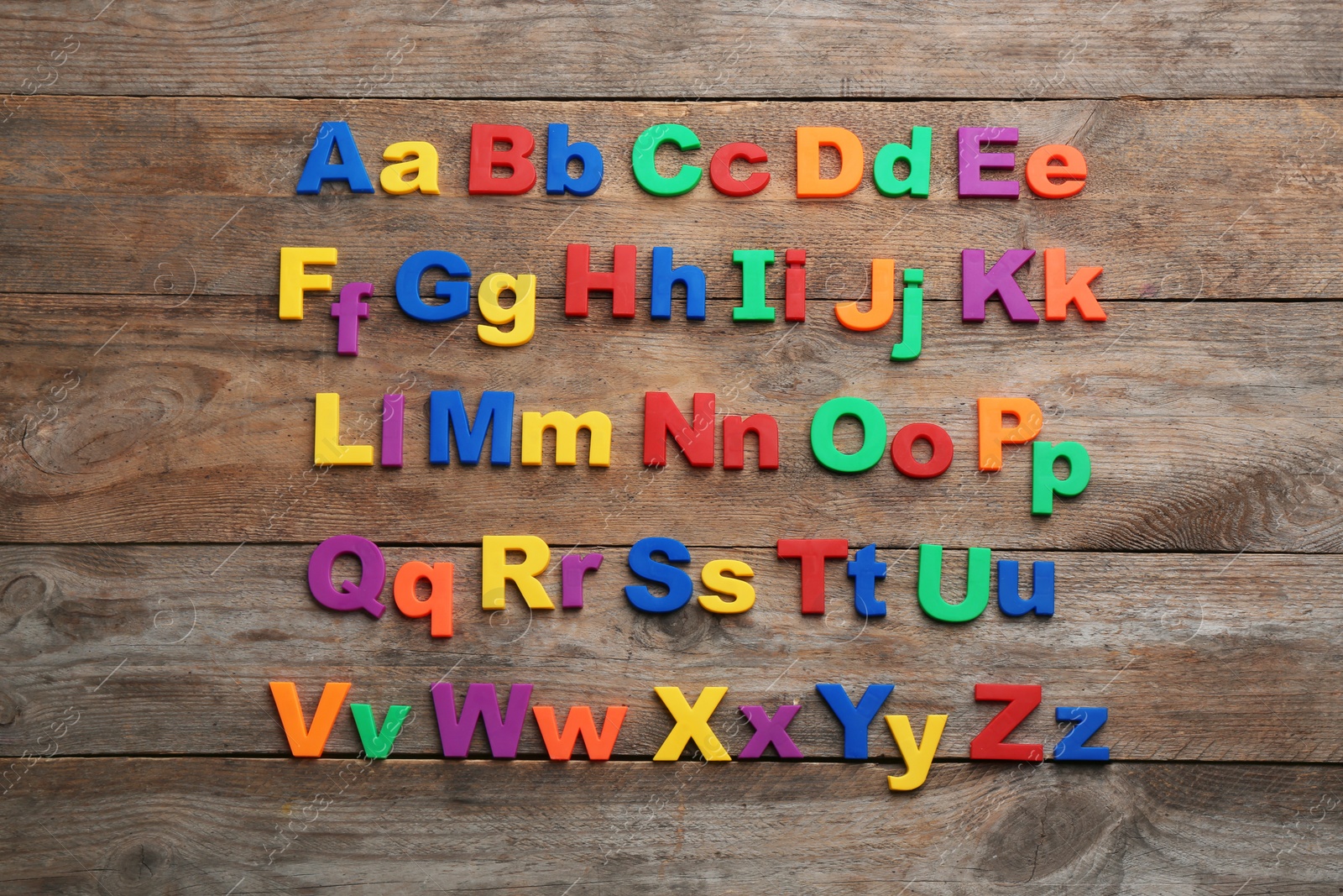 Photo of Colorful magnetic letters on wooden background, flat lay. Alphabetical order