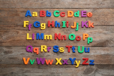 Photo of Colorful magnetic letters on wooden background, flat lay. Alphabetical order