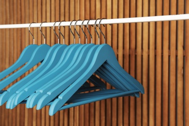 Photo of Empty hangers on rail against wooden background