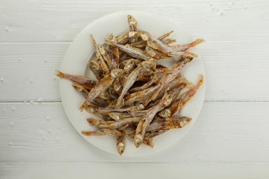 Photo of Plate with tasty dried anchovies on white wooden table, top view