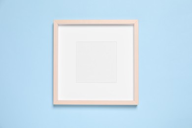 Photo of Empty photo frame on light blue background, top view. Space for design
