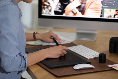 Photo of Professional retoucher working on graphic tablet at table, closeup