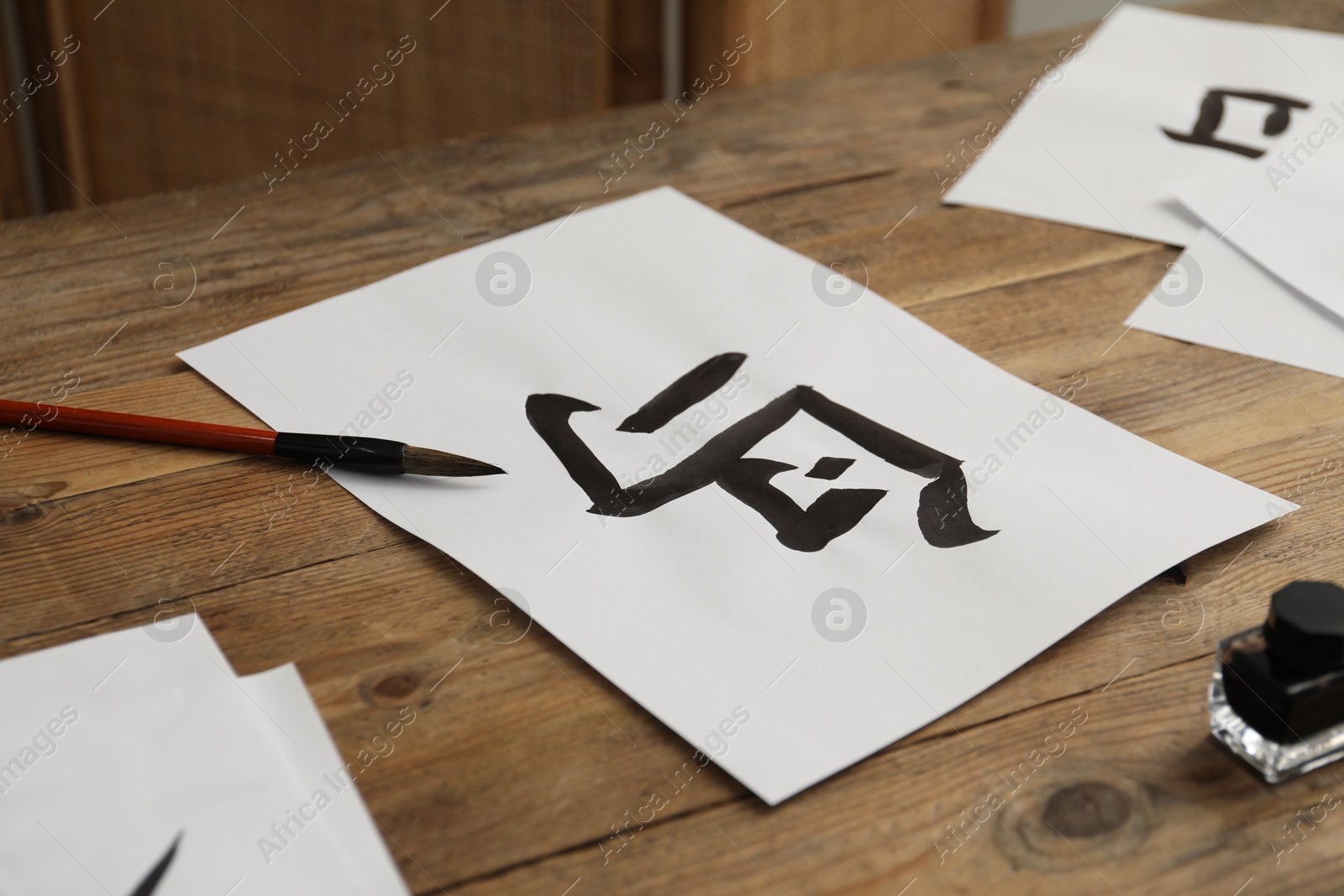 Photo of Calligraphy. Papers with written hieroglyphs, inkwell and brush on wooden table