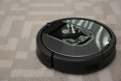 Photo of Modern robotic vacuum cleaner on light carpet