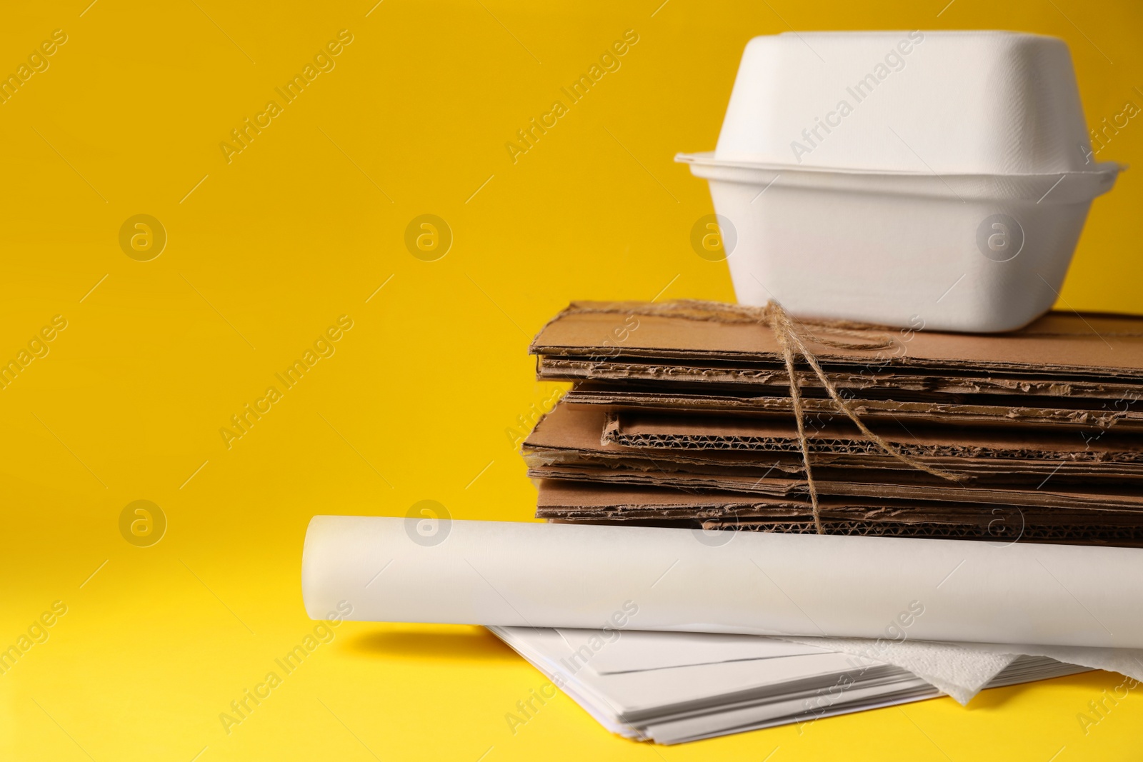 Photo of Heap of waste paper on yellow background, space for text