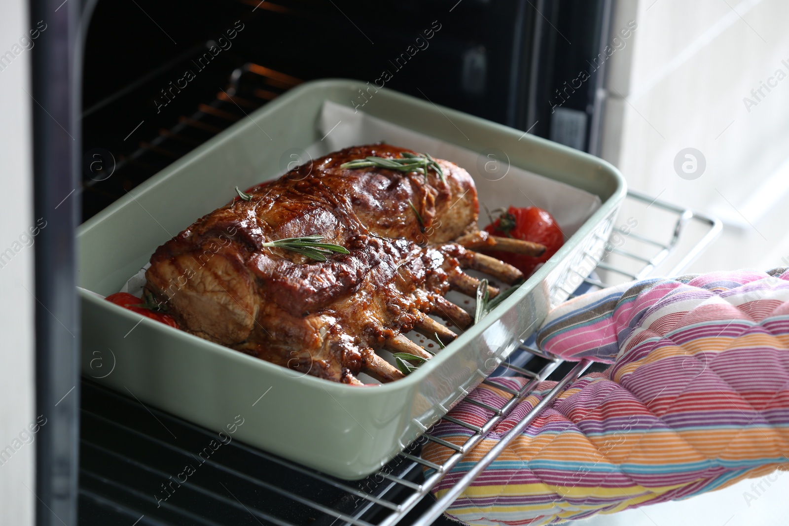 Photo of Chef taking delicious roasted ribs out of oven, closeup