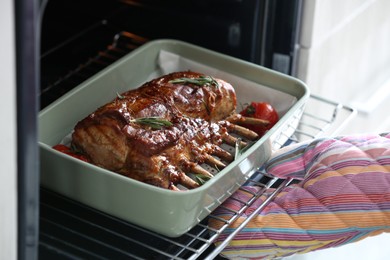 Chef taking delicious roasted ribs out of oven, closeup