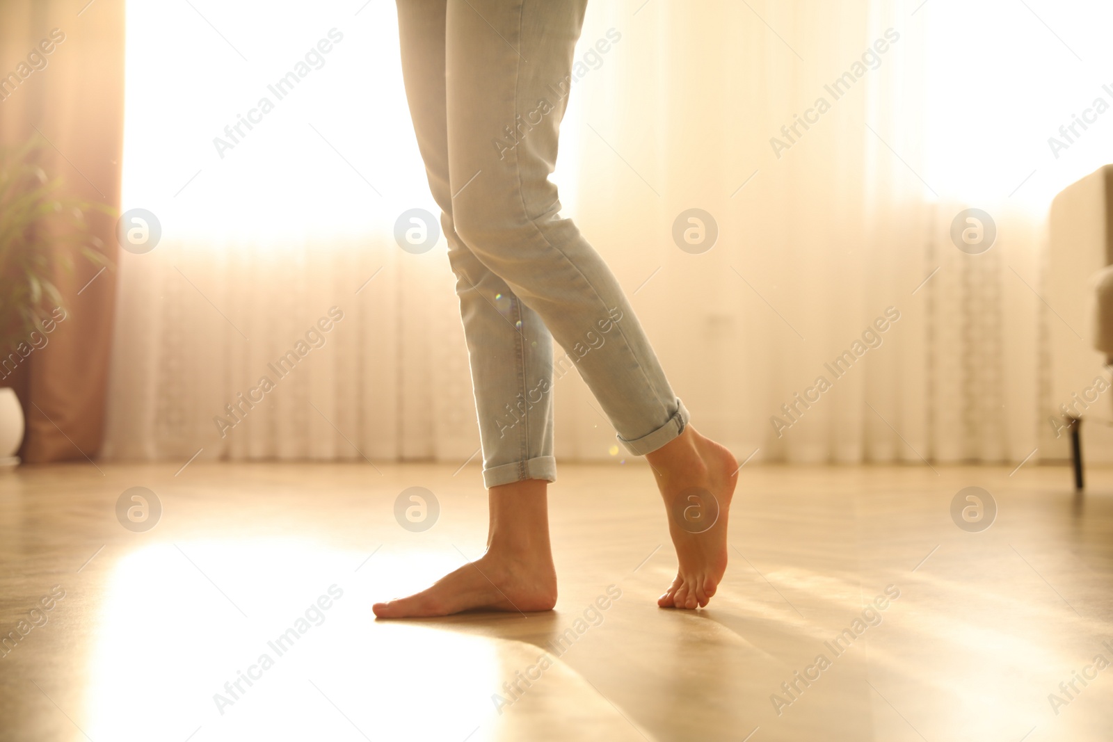 Photo of Barefoot woman at home, closeup. Floor heating system