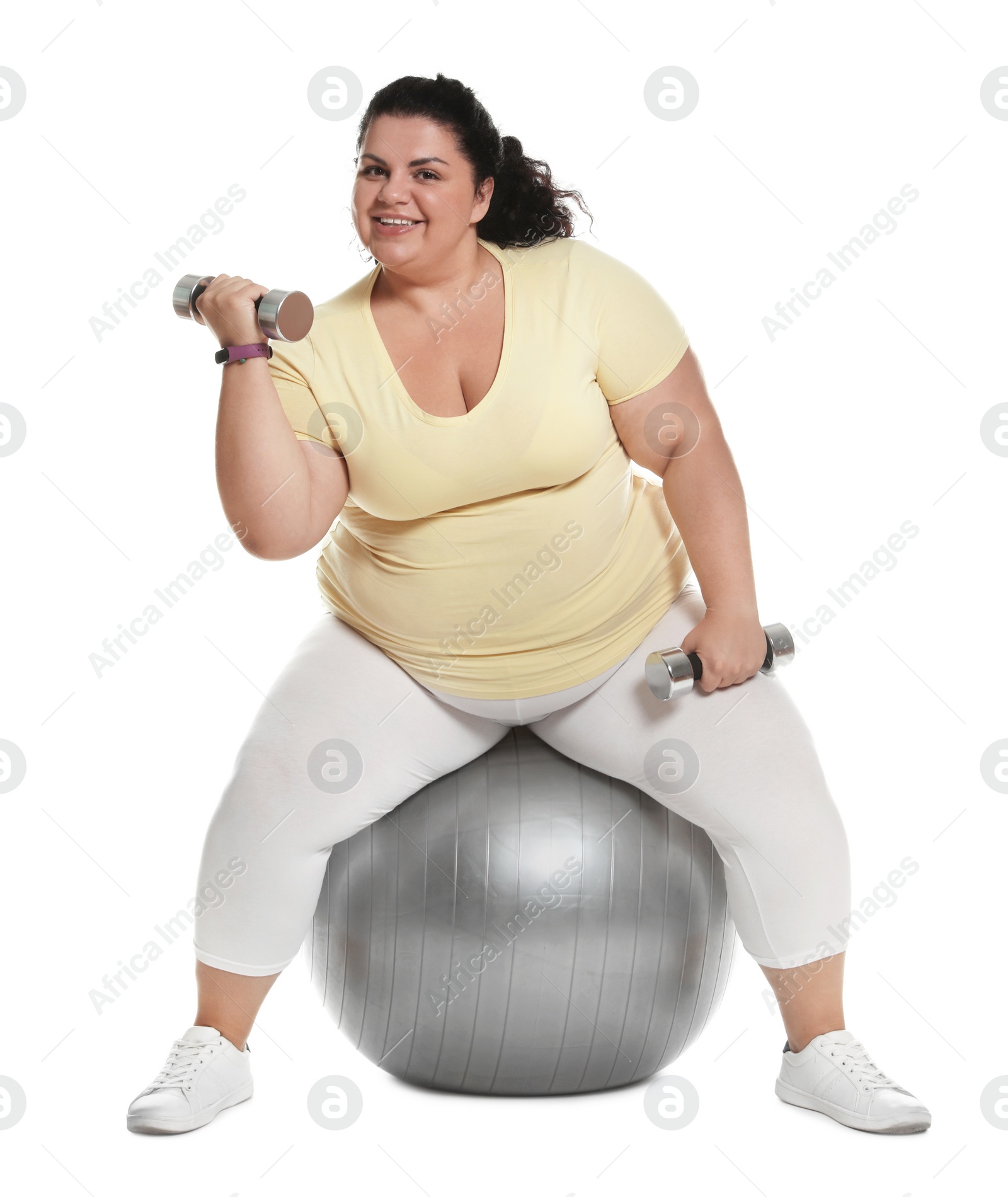 Photo of Overweight woman doing exercise on fit ball with dumbbells against white background