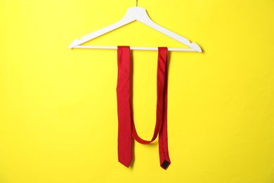 Hanger with red necktie on yellow background