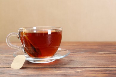 Brewing aromatic tea. Cup with teabag on wooden table. Space for text