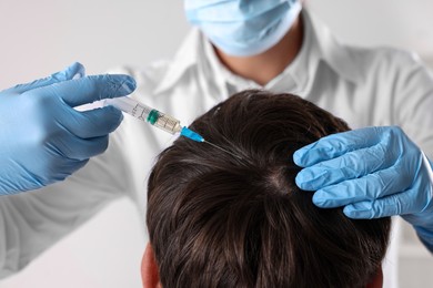 Trichologist giving injection to patient in clinic, closeup